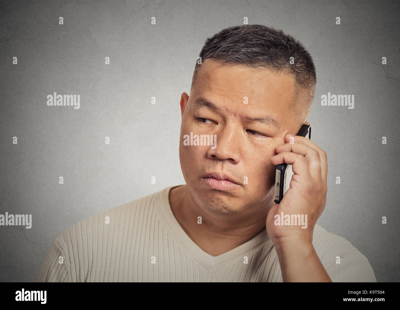 Gros plan portrait tête bouleversée, triste, déprimé, inquiet jeune homme employé père travailleur parlant sur téléphone portable isolé mur gris arrière-plan. Humain Banque D'Images