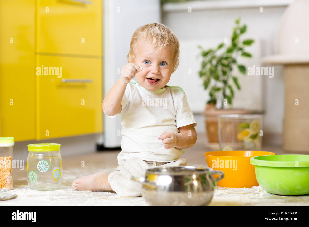Petit Enfant Garçon jouant avec des ustensiles et des denrées alimentaires en cuisine domestique Banque D'Images