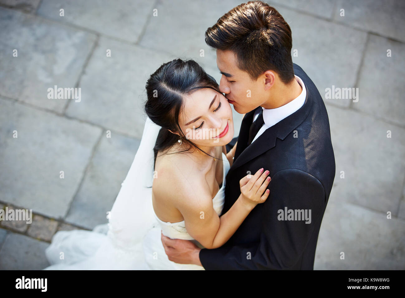 Young Asian Bride and Groom kissing embrassant la danse de plein air, high angle view. Banque D'Images