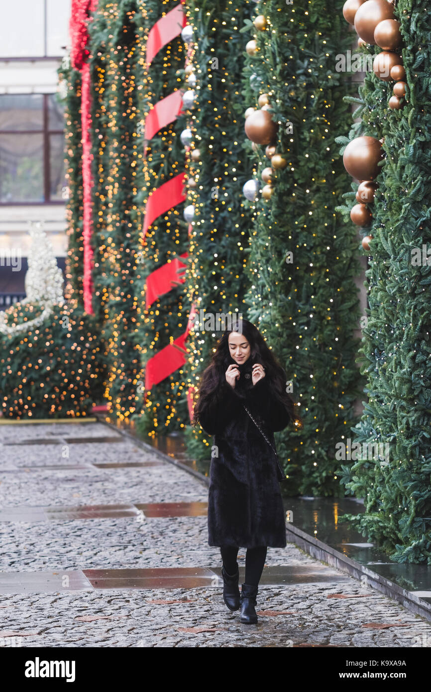 Happy woman walking in a black coat en ville, très joliment décorée pour le nouvel an Banque D'Images