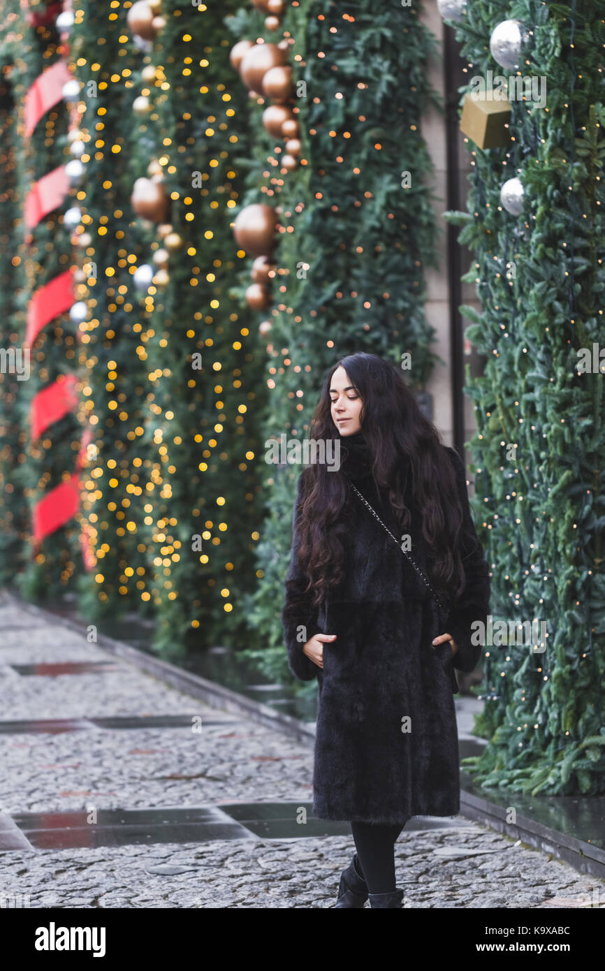 Happy woman walking in a black coat en ville, très joliment décorée pour le nouvel an Banque D'Images