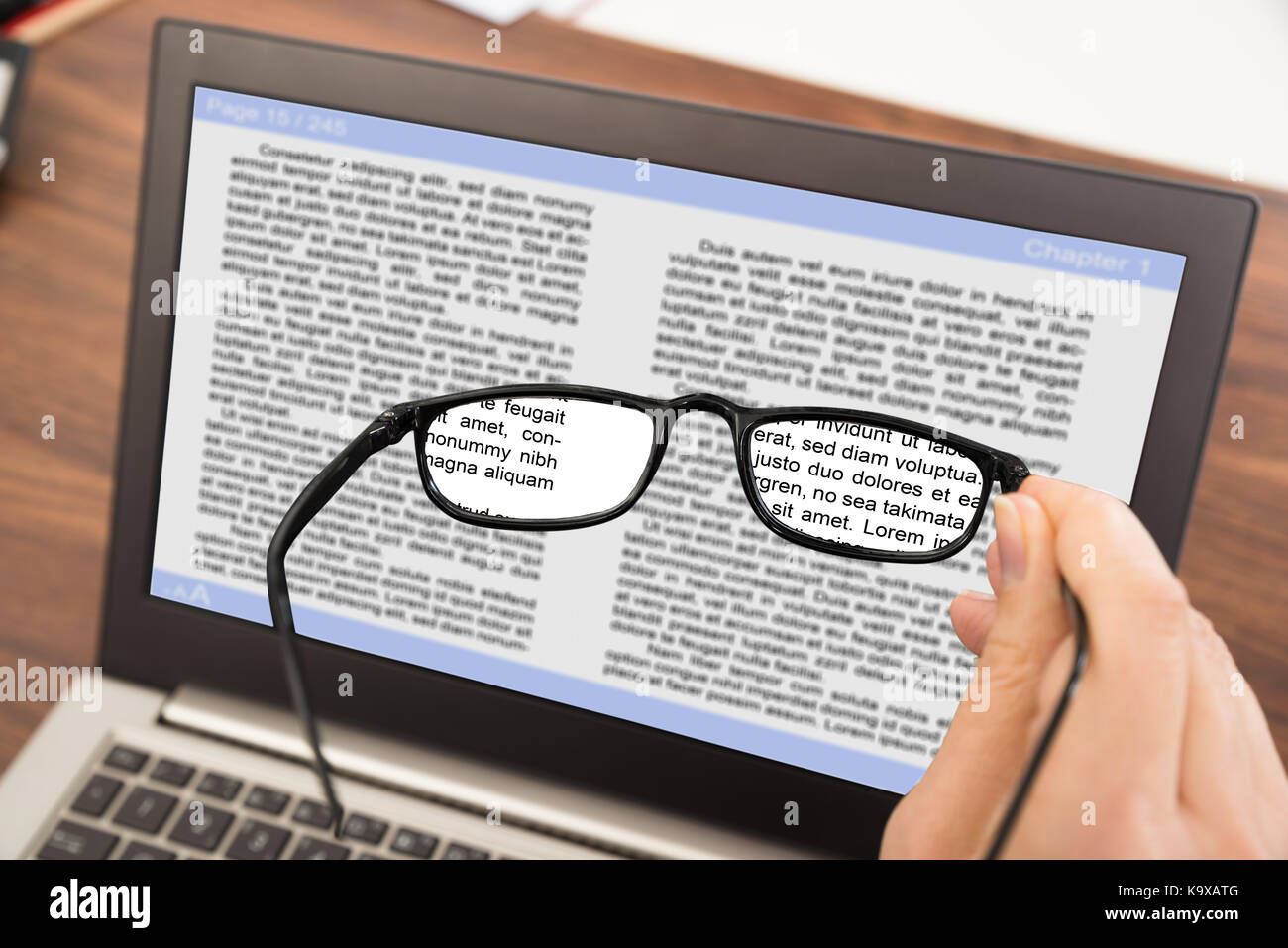Close-up of personne hand holding spectacles en font de l'ordinateur portable Banque D'Images