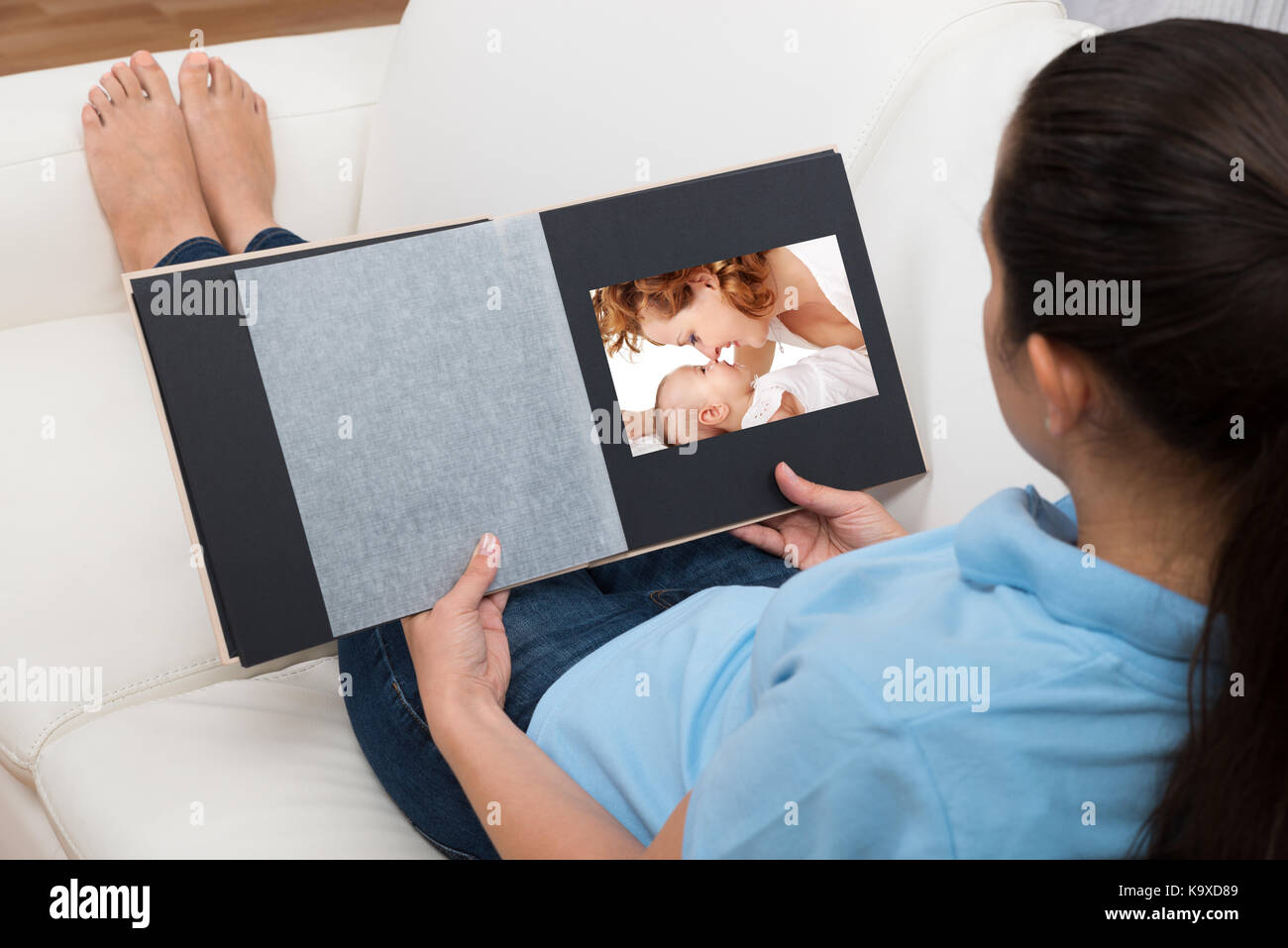 Jeune femme à la recherche de photo tout en étant assis sur le canapé dans la salle de séjour Banque D'Images