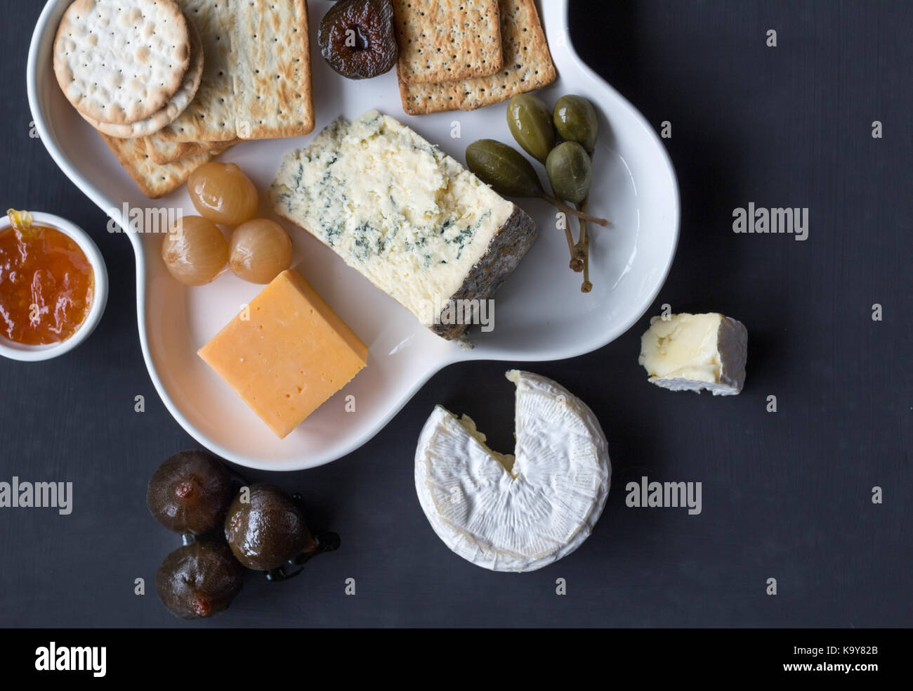 Assiette de fromage servi avec craquelins divers, confiture, figues, caper baies et oignons marinés. haut voir photo avec un espace réservé au texte Banque D'Images