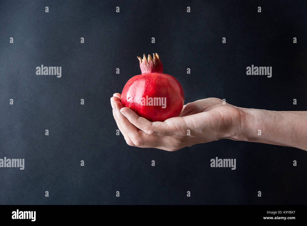 Woman hand holding venu rouge vibrant grenadier sur fond noir automne conceptuel des récoltes de l'action de copie de style d'automne modèle d'affiche de l'espace Banque D'Images