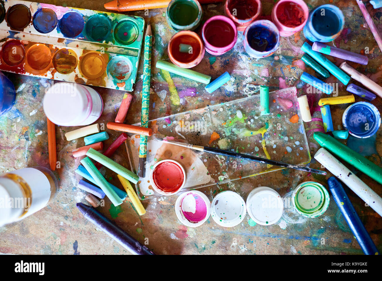 Image en arrière-plan des fournitures de peinture sur table en bois miteux : pinceaux, pastels et aquarelles peintures éclaboussé de Banque D'Images