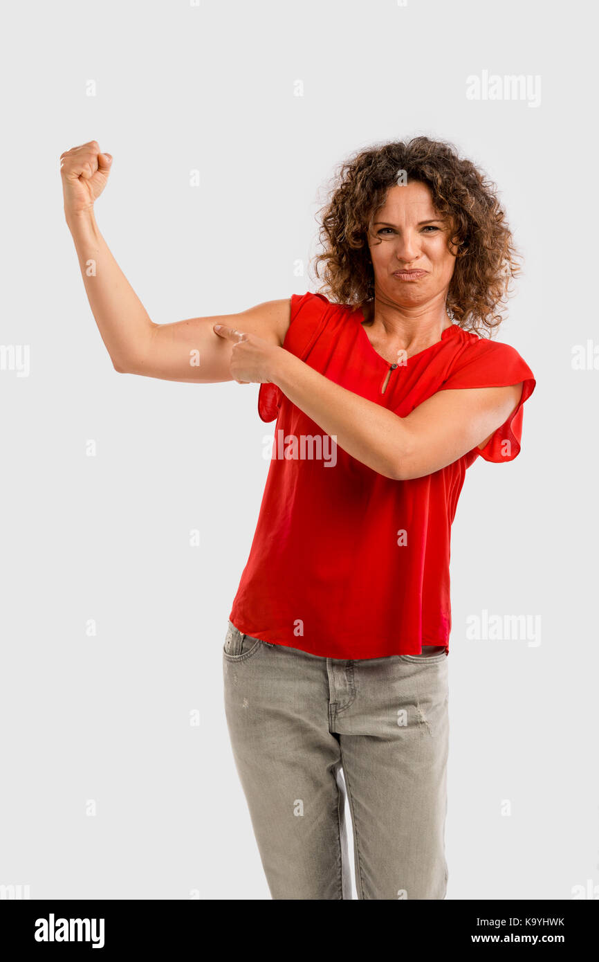 Portrait of a smiling brunette d'âge moyen en piquant dans son muscle du bras Banque D'Images