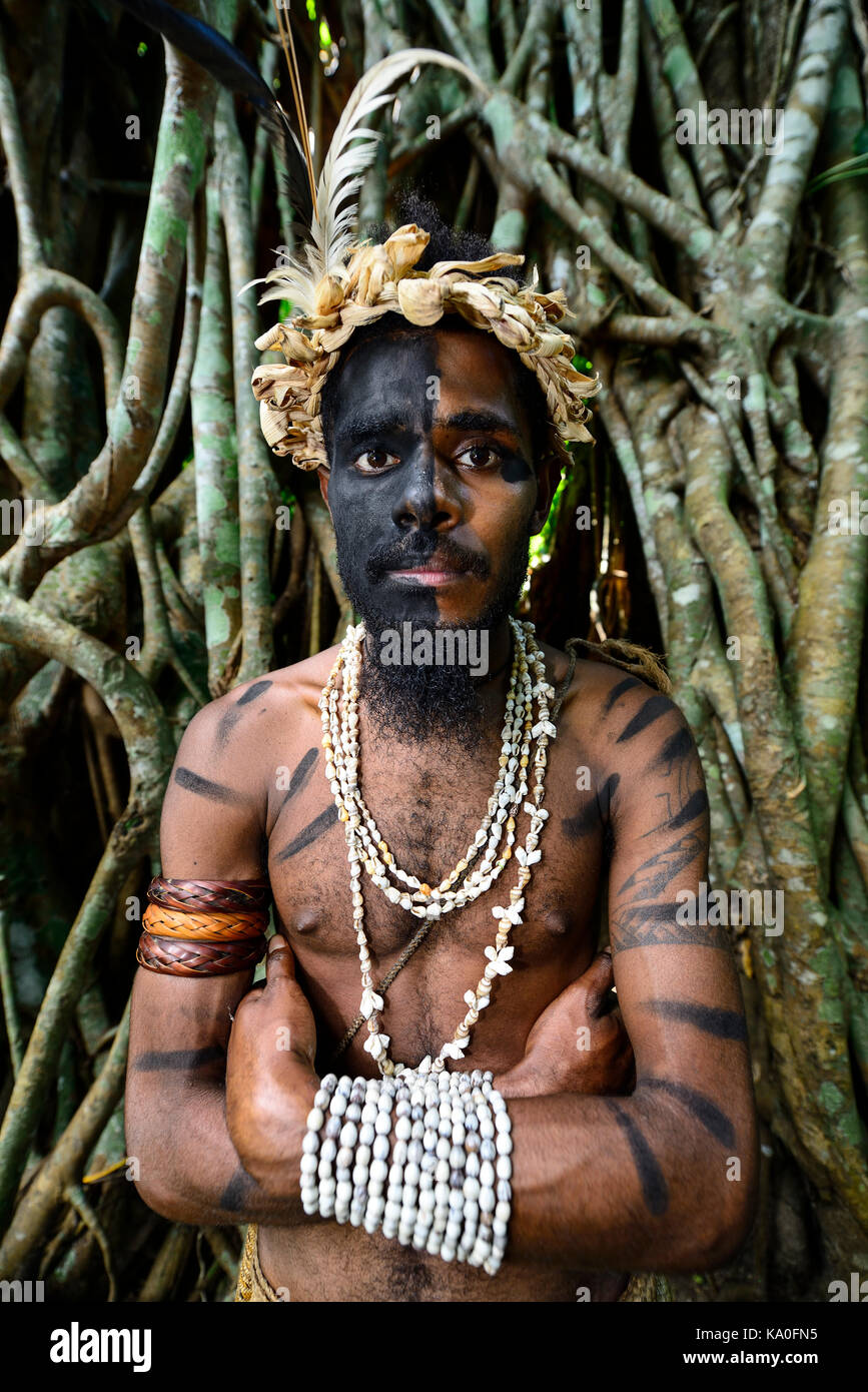 Guerrier Tribal devant les racines de l'arbre de banian (Ficus benghalensis), ekasup village culturel, l'île d'Efate, Vanuatu Banque D'Images Guerrier Tribal devant les racines de l'arbre de banian (Ficus benghalensis), ekasup village culturel, l'île d'Efate, Vanuatu Banque D'Images