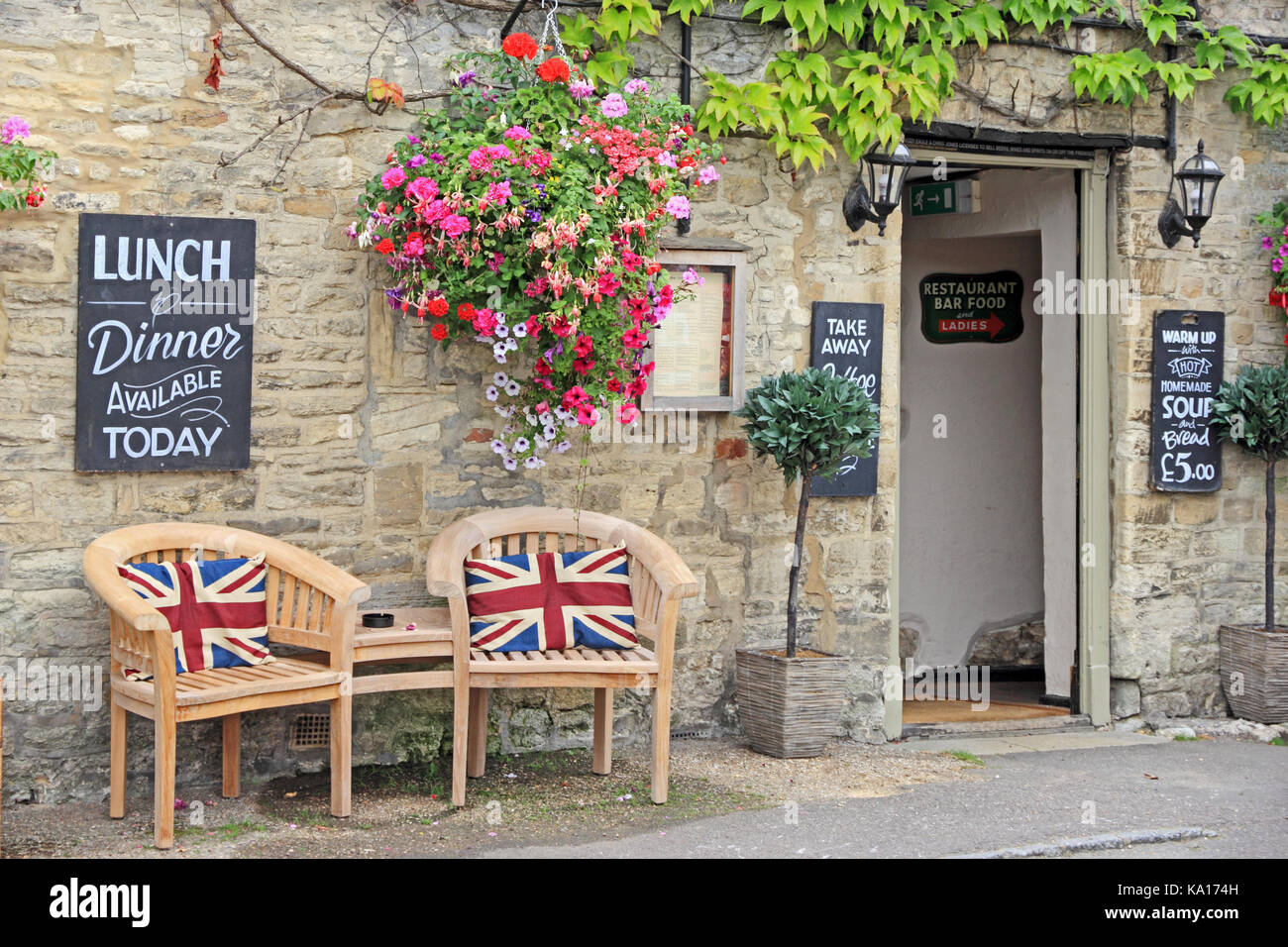 Table et chaises en bois avec coussins à l'extérieur du pavillon de l'Union public Cotswolds house. Banque D'Images