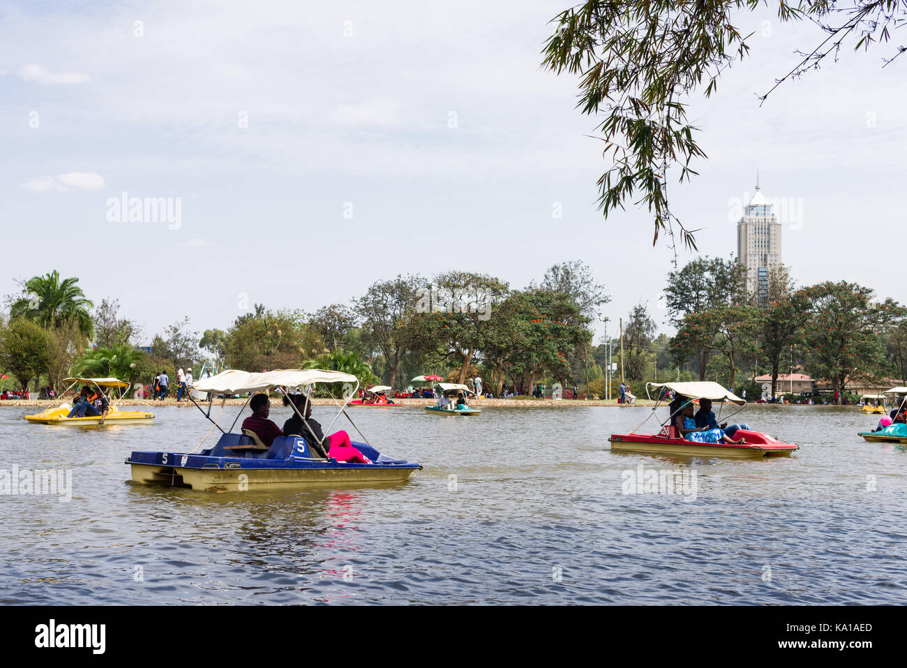 Les personnes bénéficiant de colporter des promenades en bateau ainsi que de s'asseoir près de Lake et à les regarder, Uhuru Park, Nairobi, Kenya, Afrique de l'Est Banque D'Images