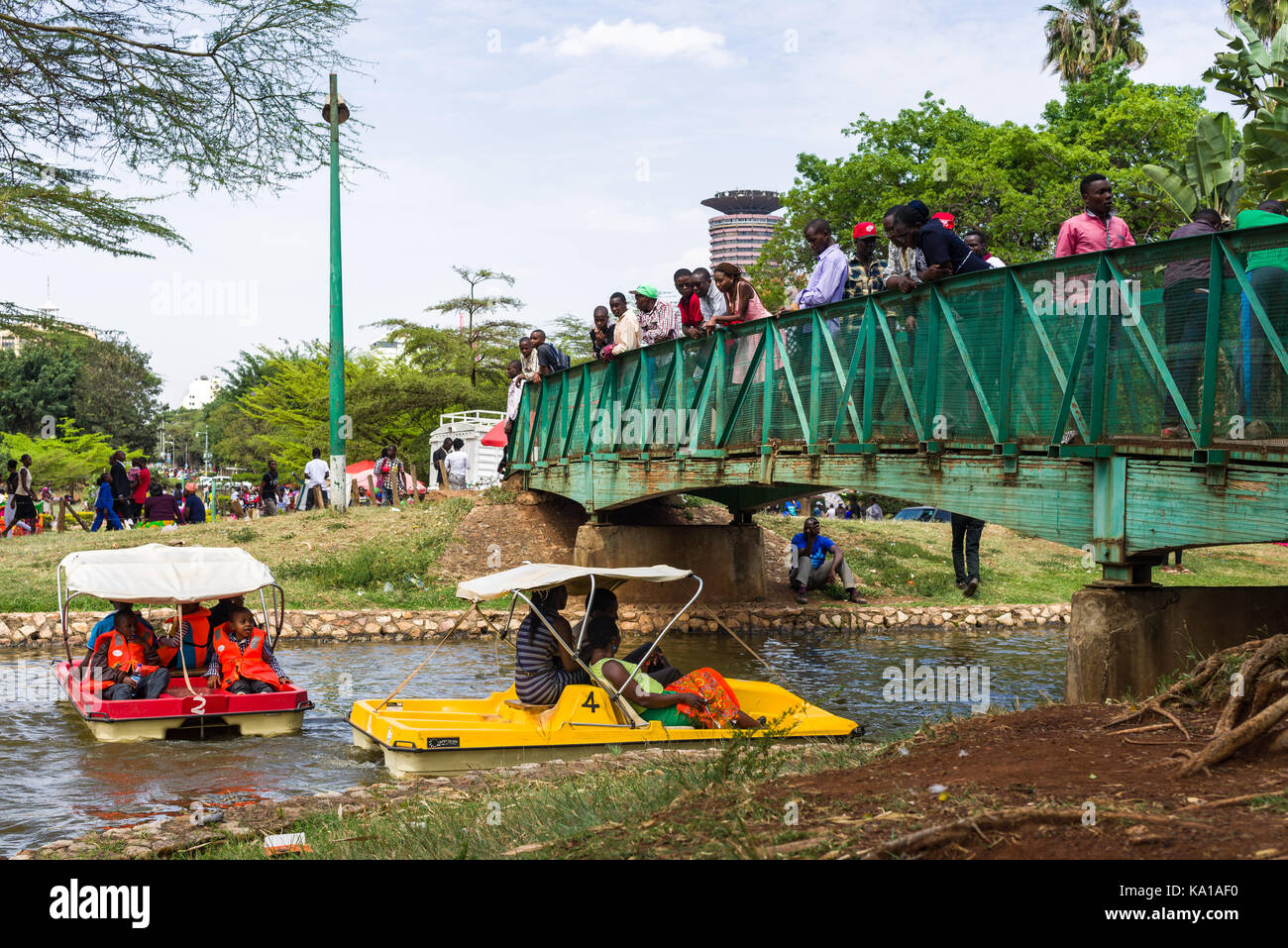 Les personnes bénéficiant de colporter des promenades en bateau dans le cadre d'un petit pont avec les gens qui regardent, Uhuru Park, Nairobi, Kenya, Afrique de l'Est Banque D'Images