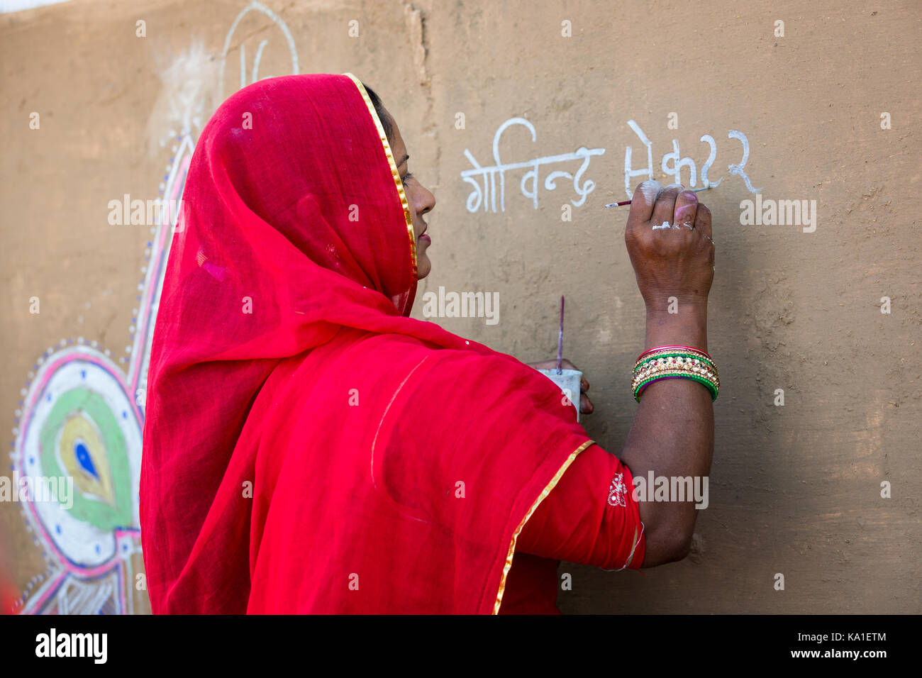 Une femme peint une fresque dans le stade à Pushkar durant la foire de chameau, Rajesthan, Inde Banque D'Images