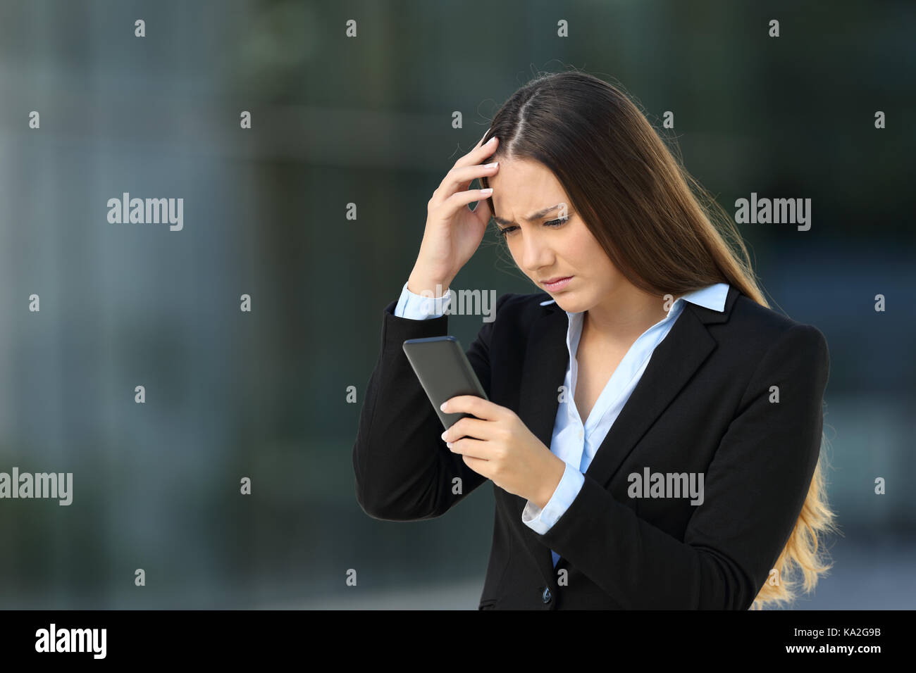 Inquiets de la lecture de mauvaises nouvelles dans un cellulaire sur la rue avec un immeuble de bureaux à l'arrière-plan Banque D'Images