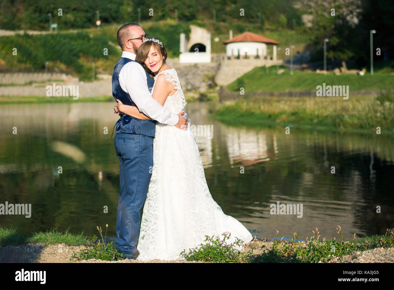 Bride and Groom hugging émotionnel en face d'un lac Banque D'Images