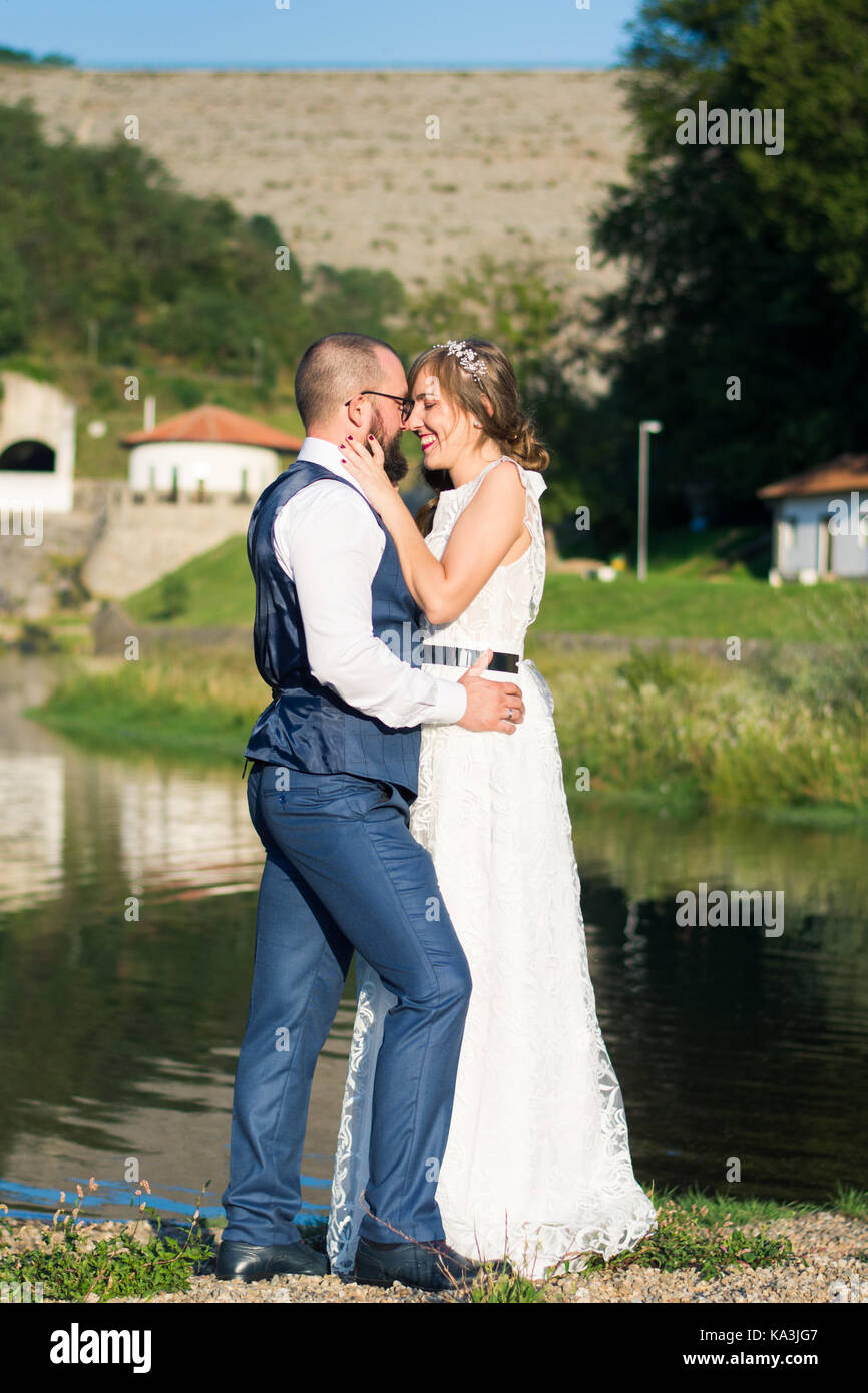 Bride and Groom hugging émotionnel en face d'un lac Banque D'Images