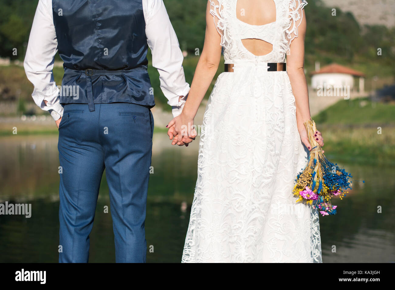 Bride and Groom holding hands in front of a lake Banque D'Images
