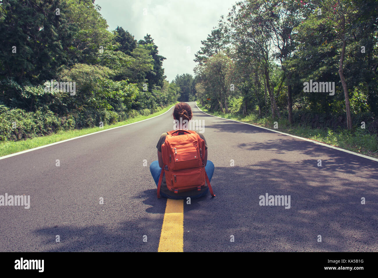 Sac à dos de transport traveler sitting on country road. retour voir photo. Banque D'Images