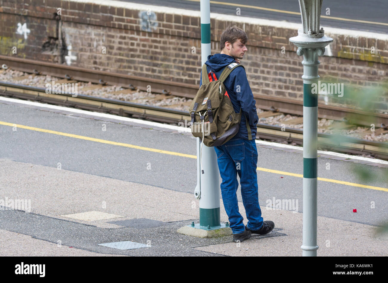 Homme debout sur une plate-forme du train en attente d'un train à une gare ferroviaire britannique en Angleterre, Royaume-Uni. Banque D'Images