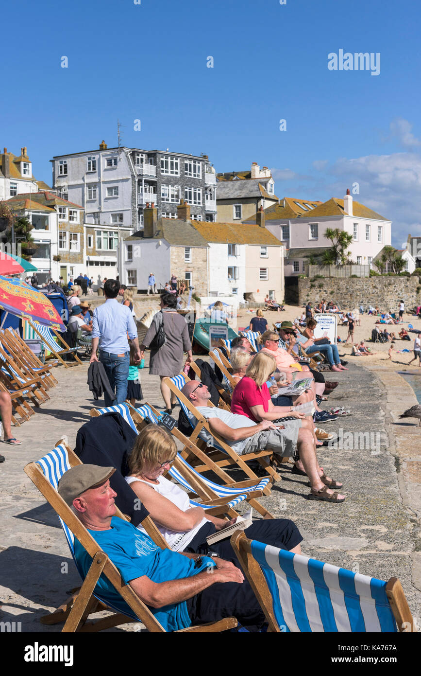 St Ives - vacanciers, de vous détendre dans des chaises longues sur le quai à St Ives harbour beach, à Cornwall. Banque D'Images