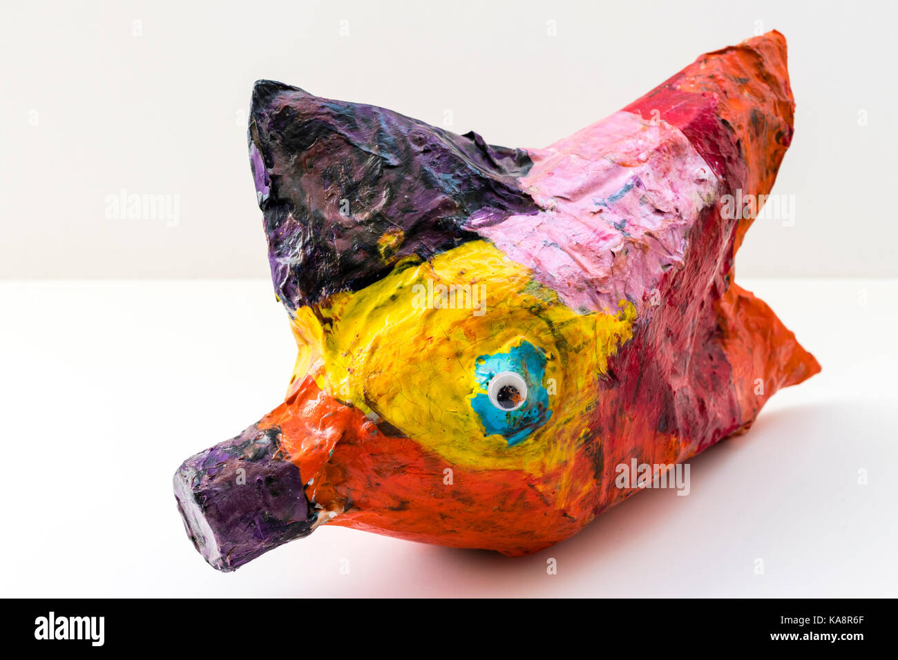 L'Angleterre. Création de l'enfant, poisson papier mâché multi-couleur sur fond gris clair. Banque D'Images