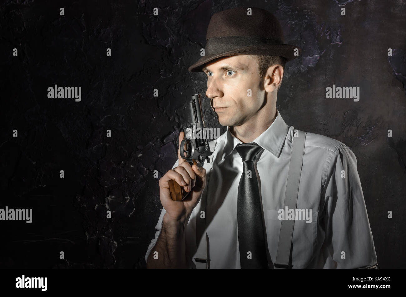 Photo noir et blanc d'un détective privé avec une arme à deux mains. Dans l'élégant Agent hat. L'homme reste l'avant à l'appareil photo. Il porte la chemise classique avec Banque D'Images Photo noir et blanc d'un détective privé avec une arme à deux mains. Dans l'élégant Agent hat. L'homme reste l'avant à l'appareil photo. Il porte la chemise classique avec Banque D'Images