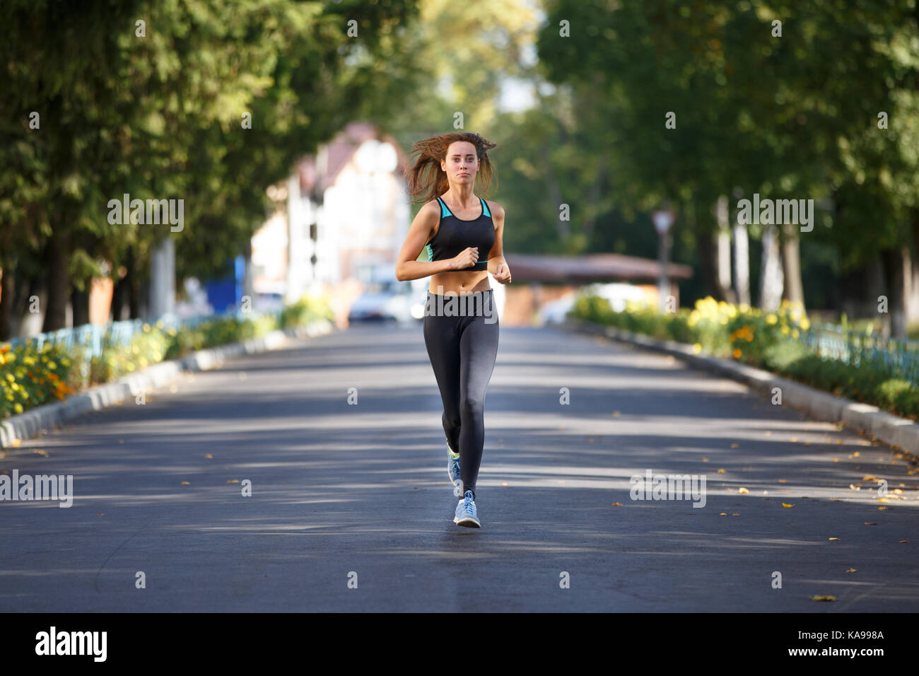 Young smiling woman running sportive sur la route dans la matinée. fitness jogging girl in park Banque D'Images