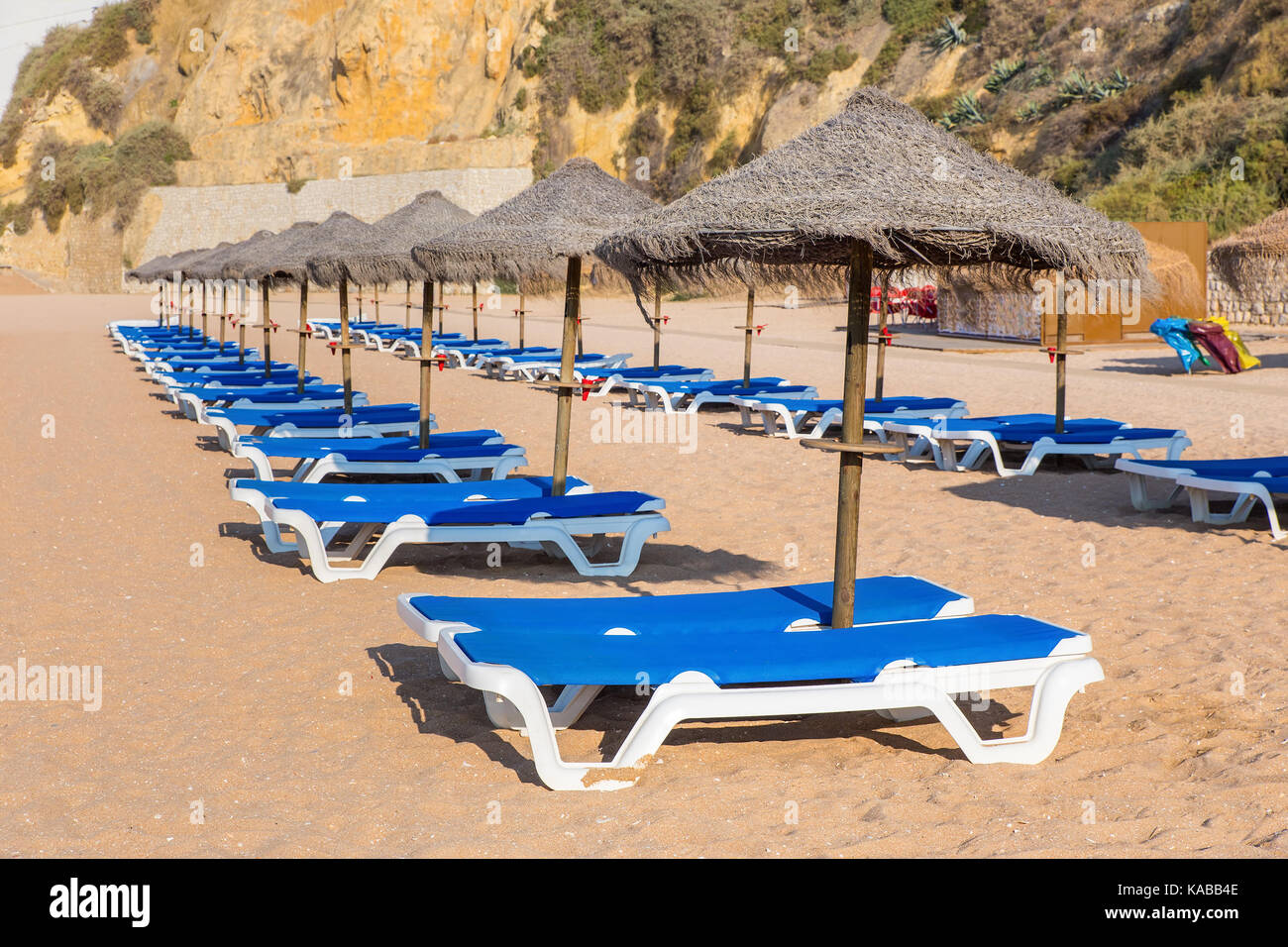 Rangées de parasols de plage en osier et des lits de plage bleu Banque D'Images