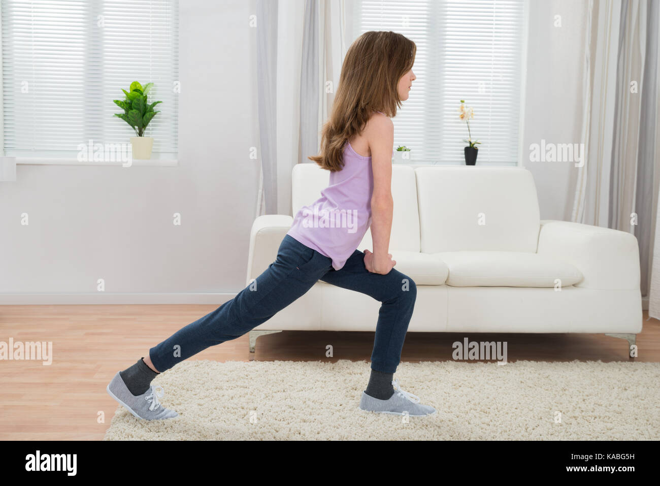 Fille dans l'exercice de sport dans la salle de séjour Banque D'Images