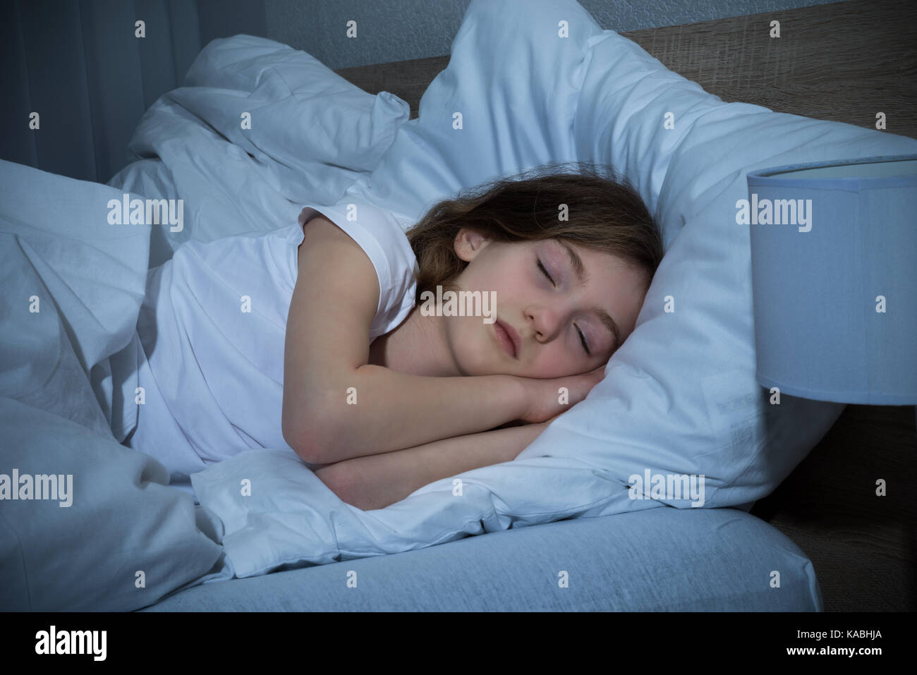 Cute Girl Sleeping On lit dans une chambre sombre Banque D'Images