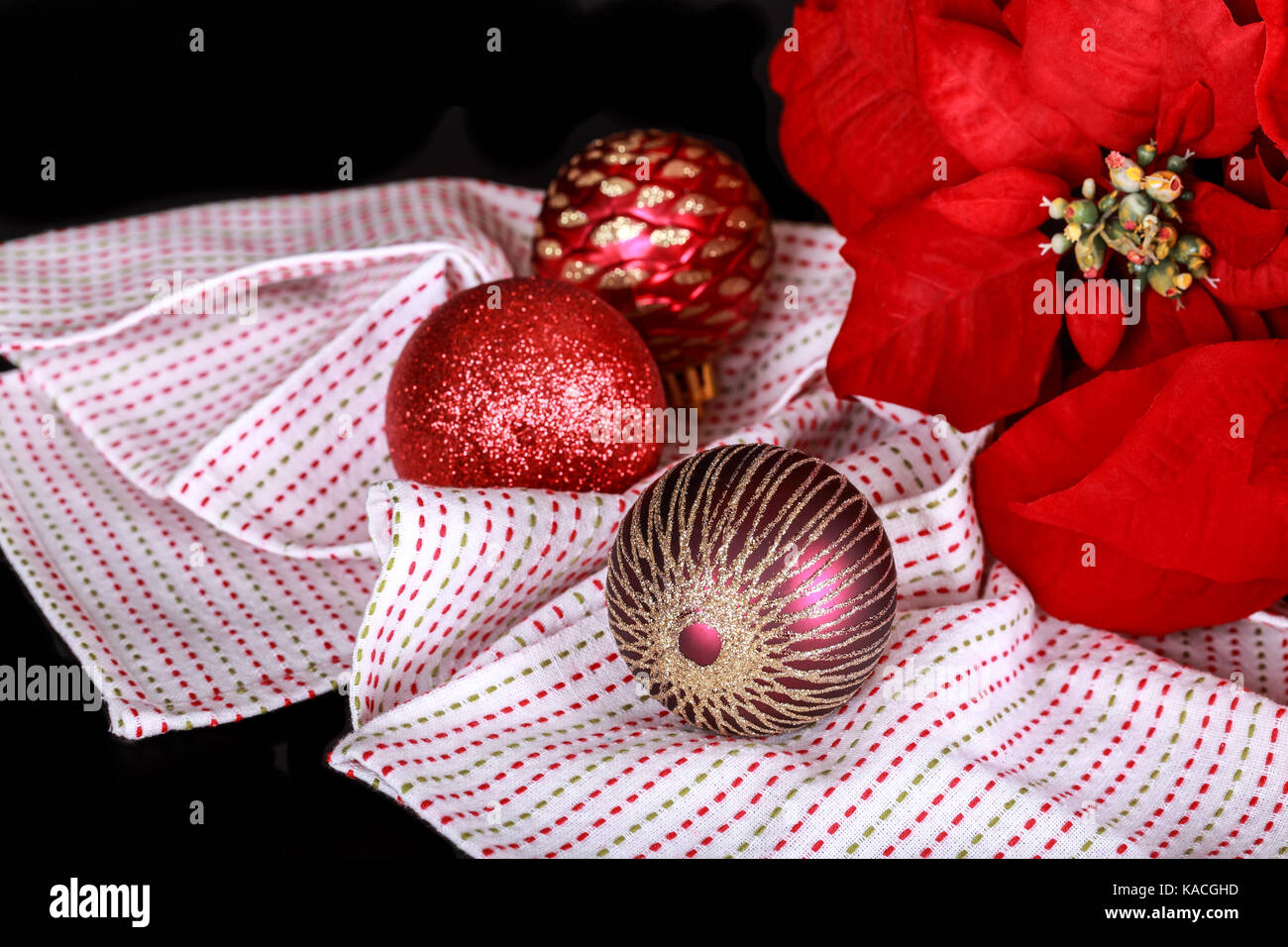 Décoration de Noël, le poinsettia rouge, boule de noël et tissu sur un fond noir. Banque D'Images