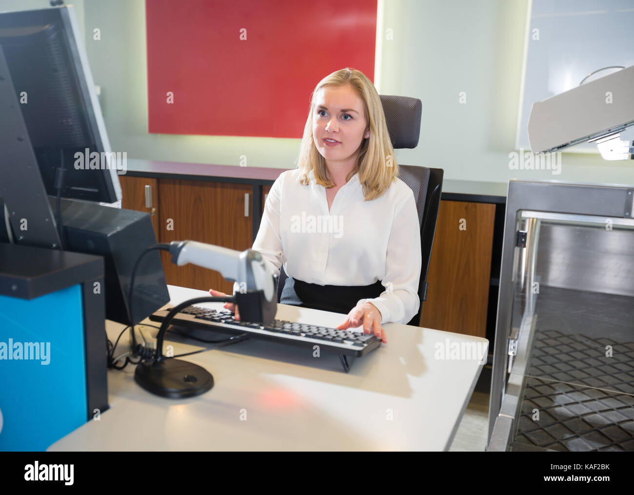 Le personnel féminin à l'aide d'ordinateur à l'enregistrement à l'aéroport Banque D'Images