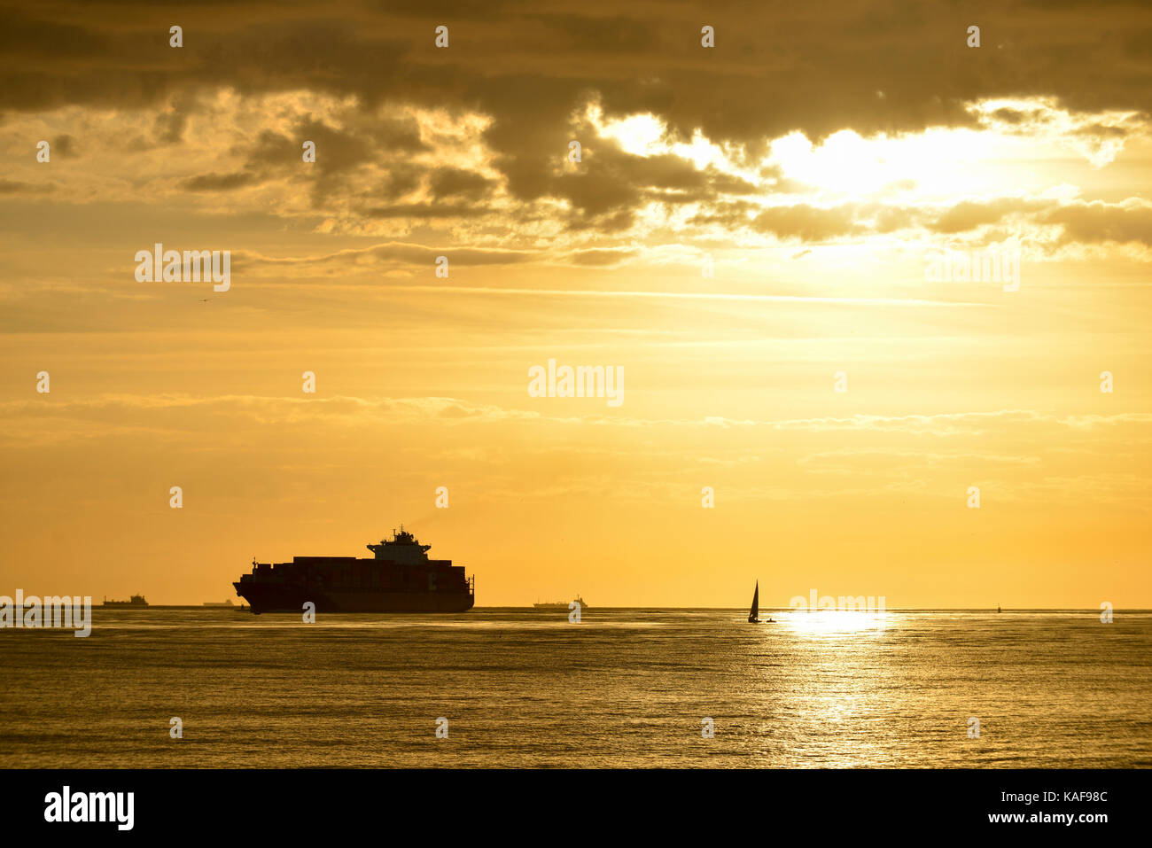 Le Havre (Normandie, région du nord-ouest de la France) : container ship et voilier au large de la côte au coucher du soleil Banque D'Images