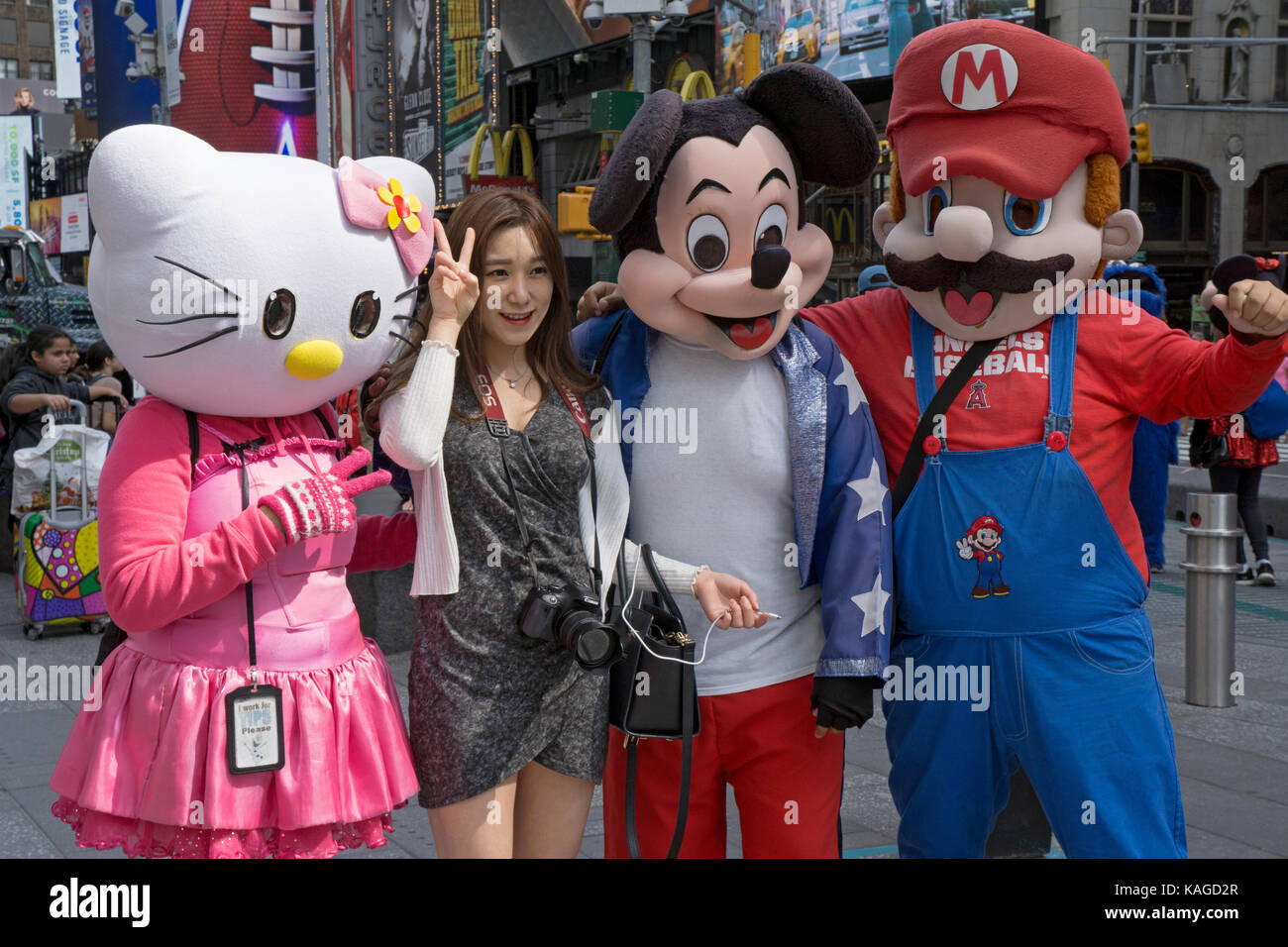 Un touristes asiatiques pose pour des photos avec des artistes habillés comme des personnages de bande dessinée et de la télévision. Times Square, New York City. Banque D'Images
