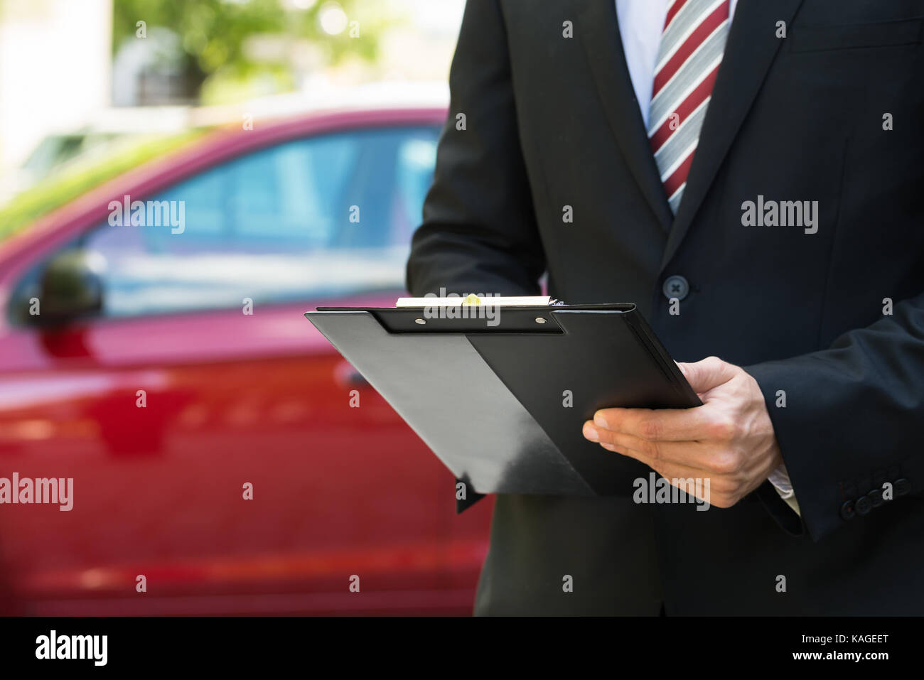 Close-up of a man standing in front of car holding clipboard dans sa main Banque D'Images