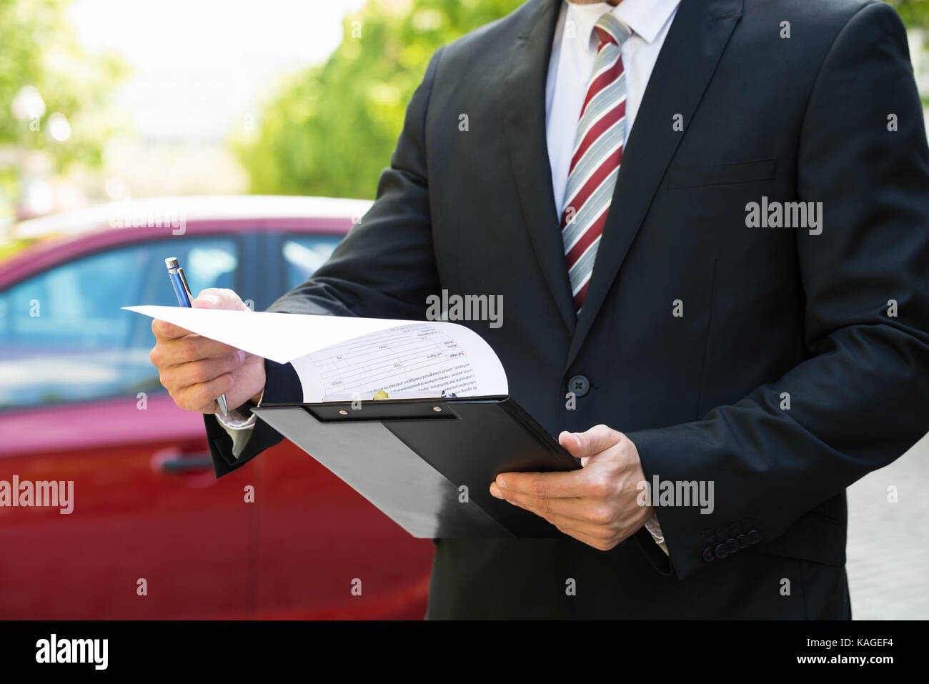 Close-up of a man standing in front of car holding clipboard dans sa main Banque D'Images