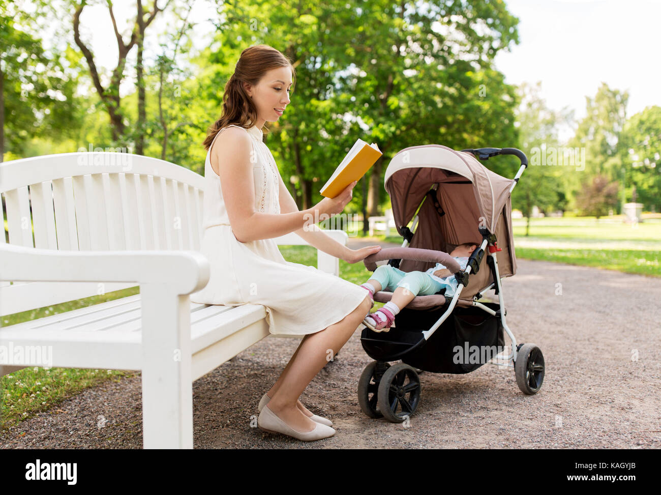 Mère avec enfant en poussette reading book at park Banque D'Images