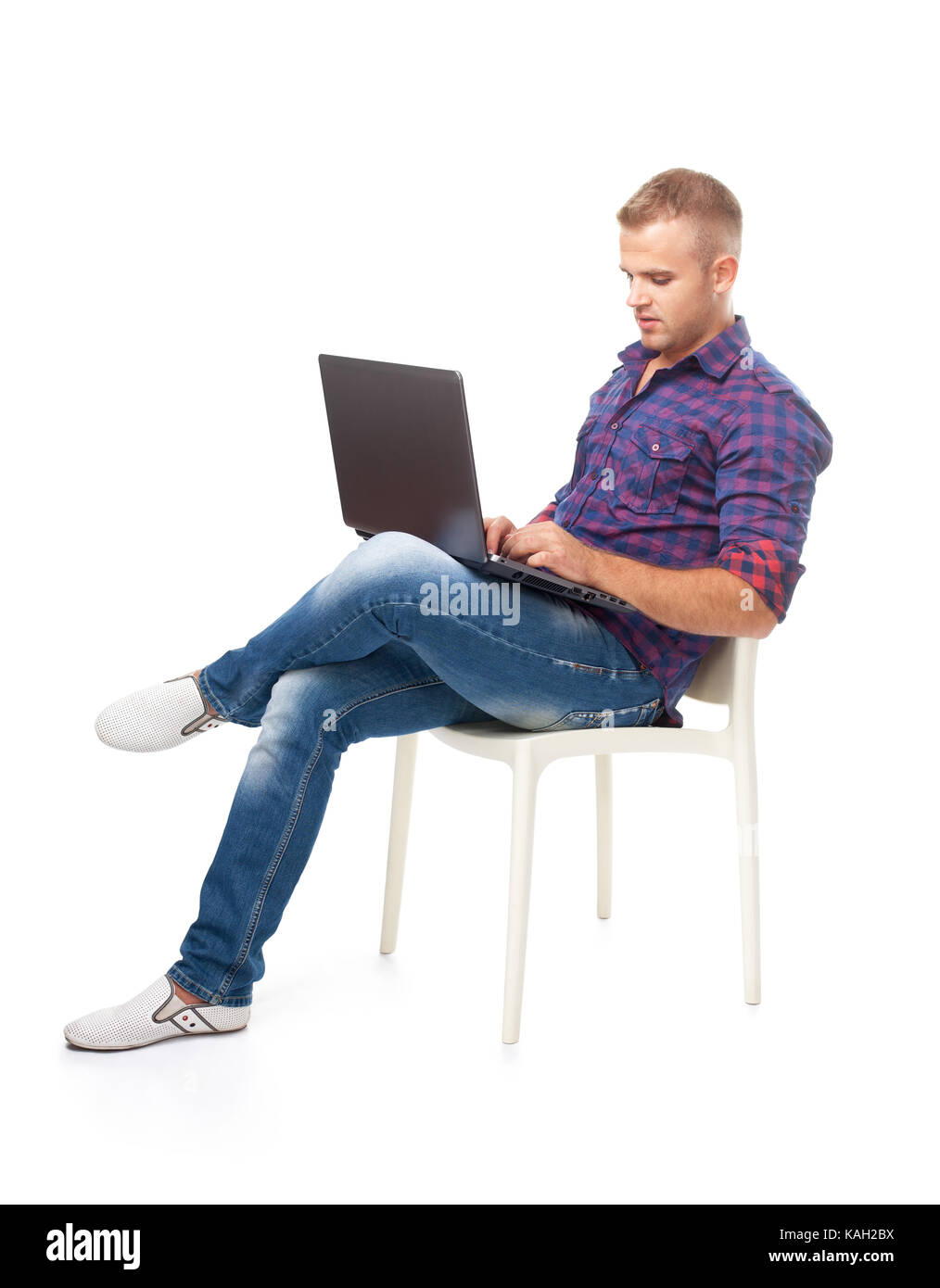 Young man sitting in chair et travaillant sur un ordinateur portable isolé sur fond blanc Banque D'Images