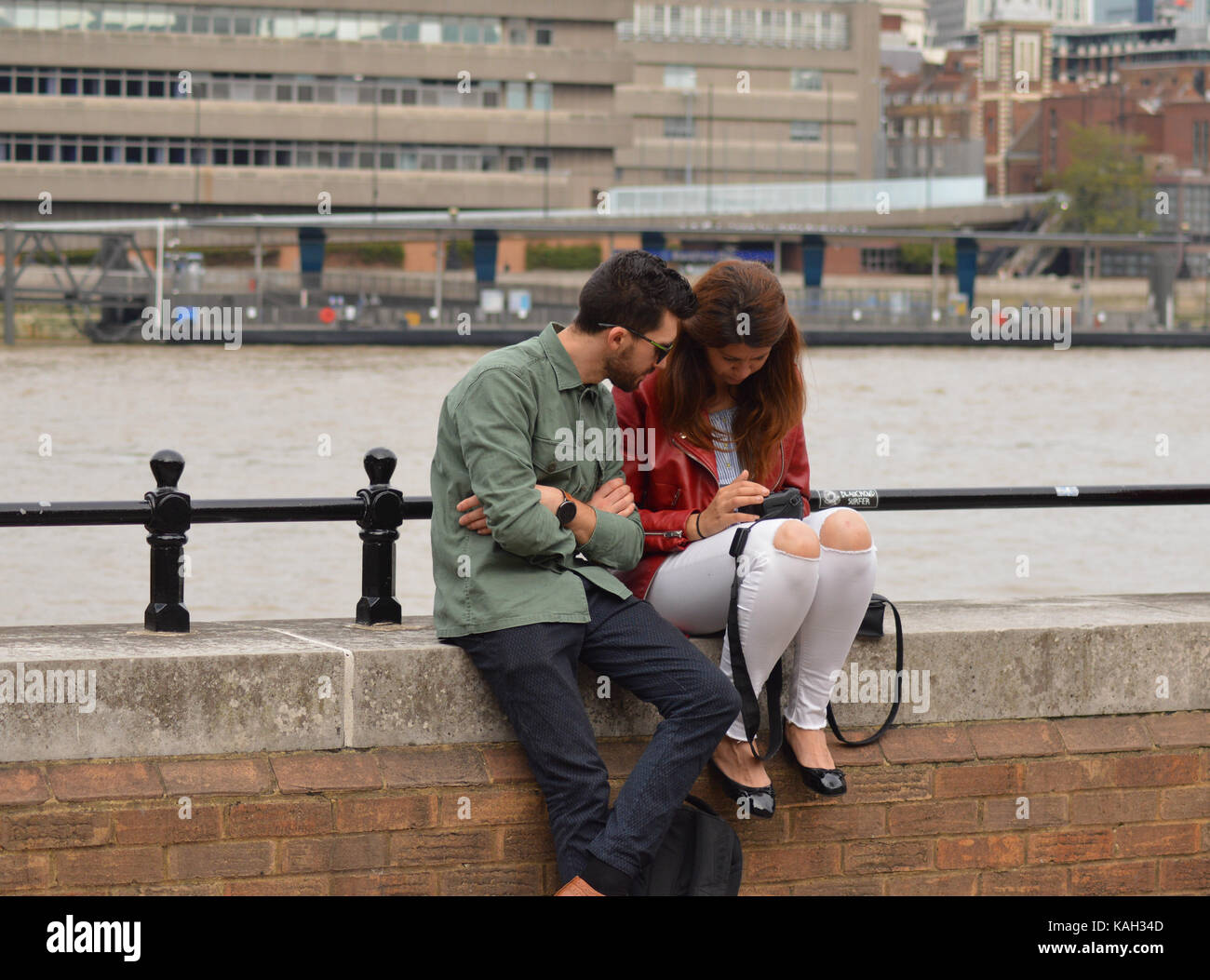 Jeune couple sur la rive sud de Londres assis sur le mur de leurs photographies Banque D'Images