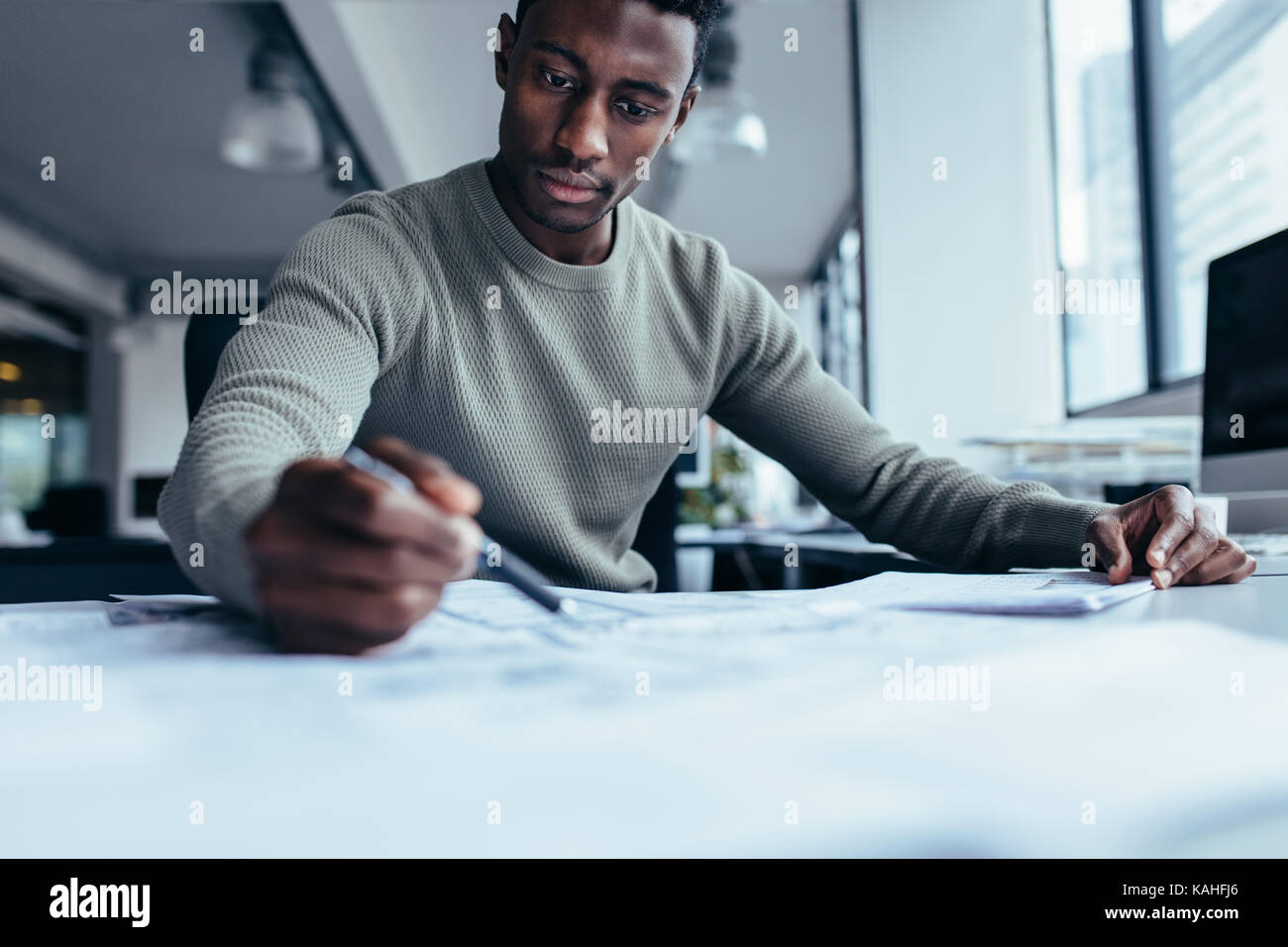 Businessman pointing at building plan dans le bureau. Black Man working on construction plan. Banque D'Images