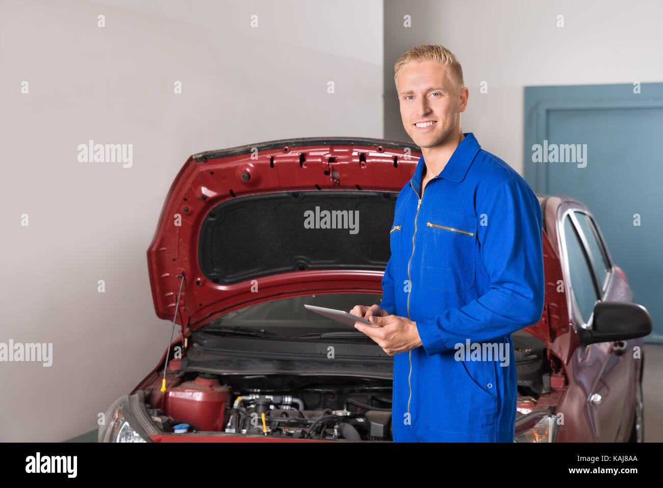 Smiling young mechanic using digital tablet in garage Banque D'Images