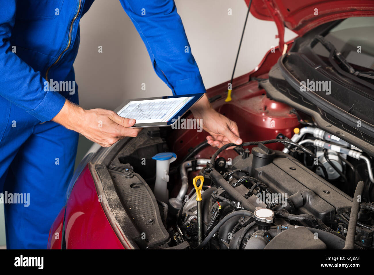 Close-up of mechanic using digital tablet lors de l'examen du moteur de voiture en garage Banque D'Images