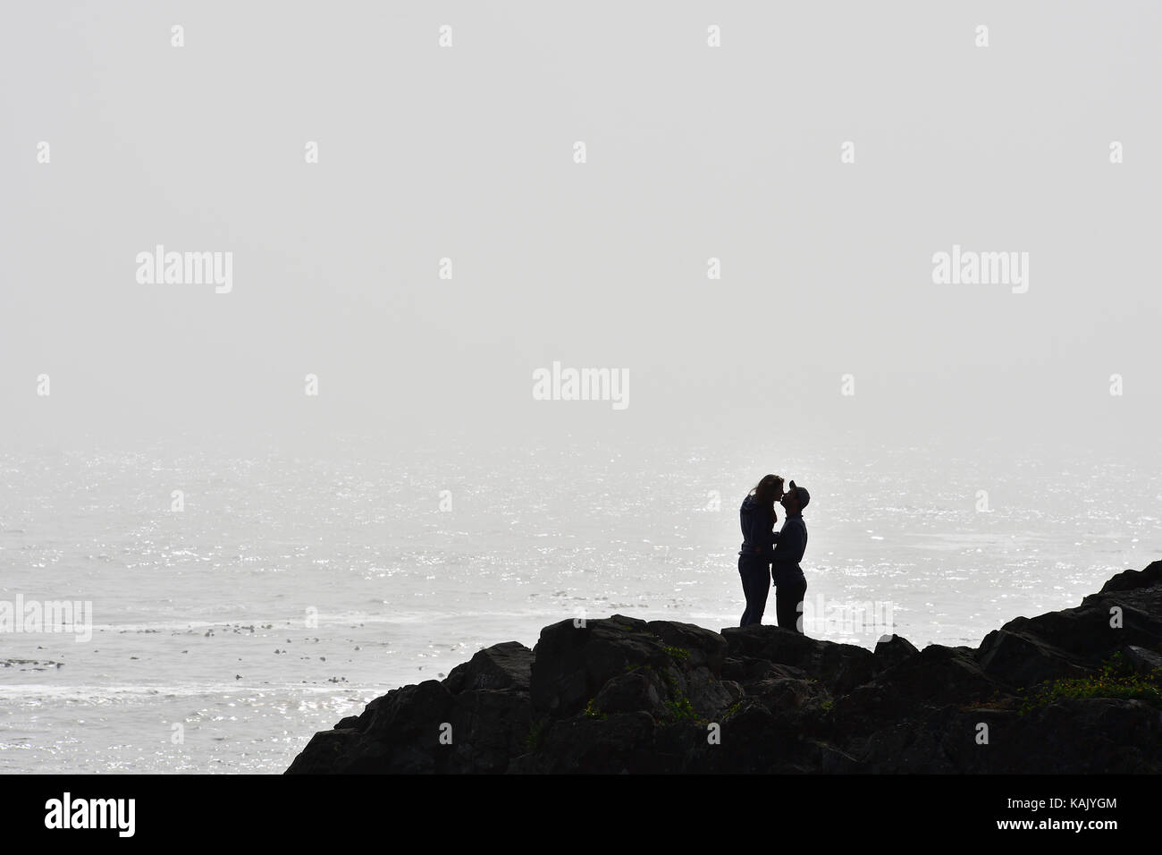 Une silhoutte of mountain range at sunset un couple sur le bord de la côte sauvage partager une étreinte dans le brouillard de l'océan, sur la côte ouest de l'île de Vancouver, Colombie-Britannique, Canada Banque D'Images