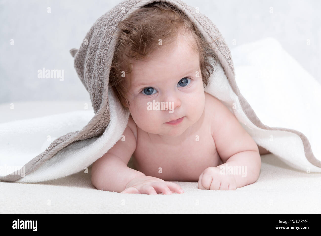 Mignon bébé nouveau-né fille avec de beaux yeux bleus sur un couvre-lit  blanc terry. adorable bébé à la recherche dans le cadre d'une couverture  blanche ou d'une serviette. happy baby bébé dans