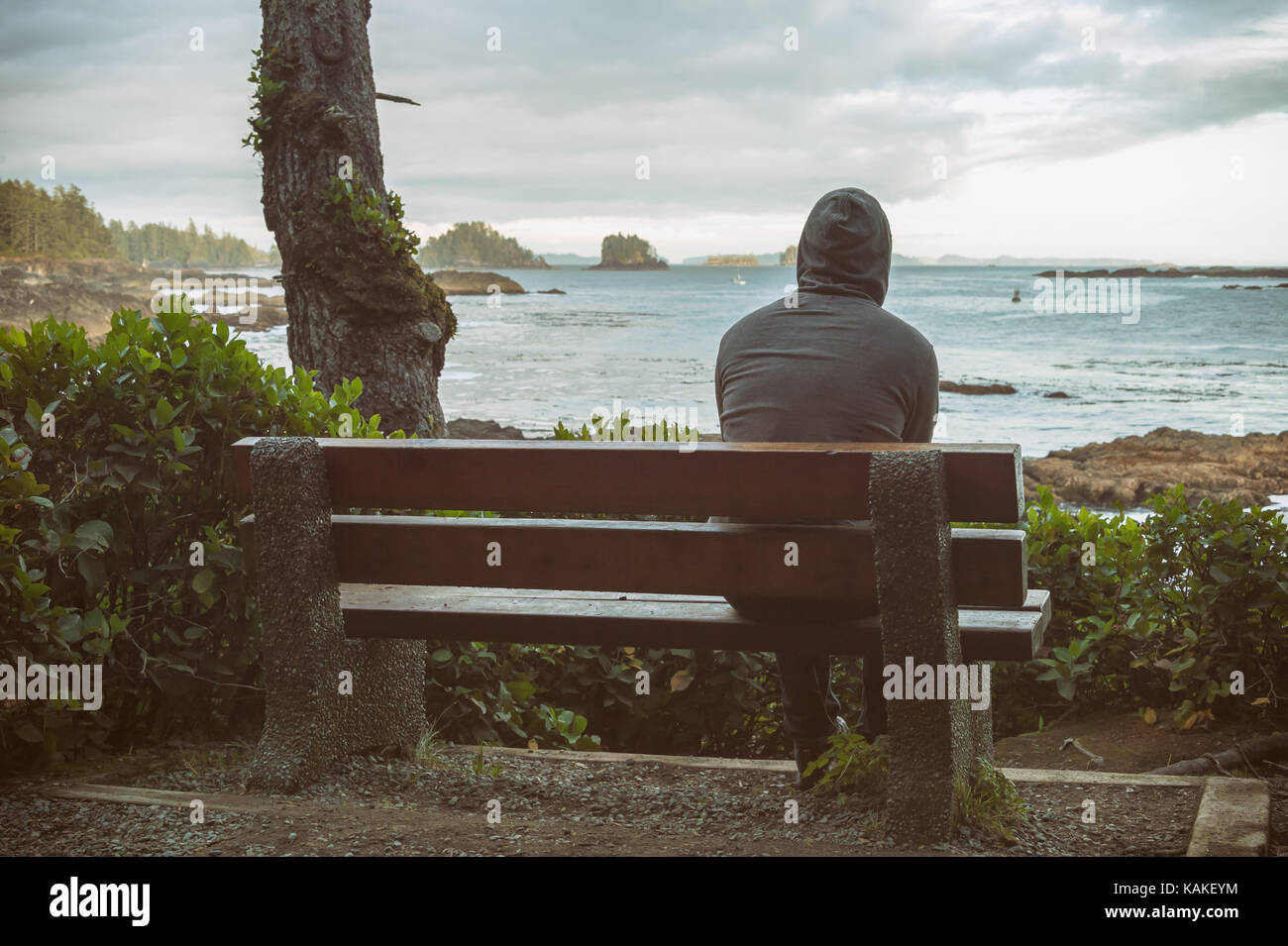 L'homme triste et solitaire assis sur un banc avec vue sur la mer sur l'île de Vancouver Banque D'Images