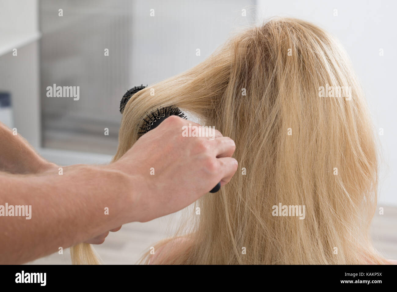 Image recadrée de coiffeur mâle brushing woman's hair at salon Banque D'Images
