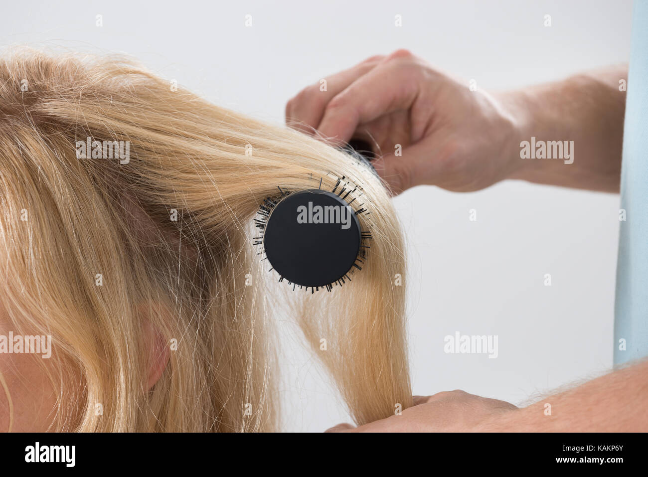Image recadrée de coiffeur mâle brushing woman's hair at salon Banque D'Images