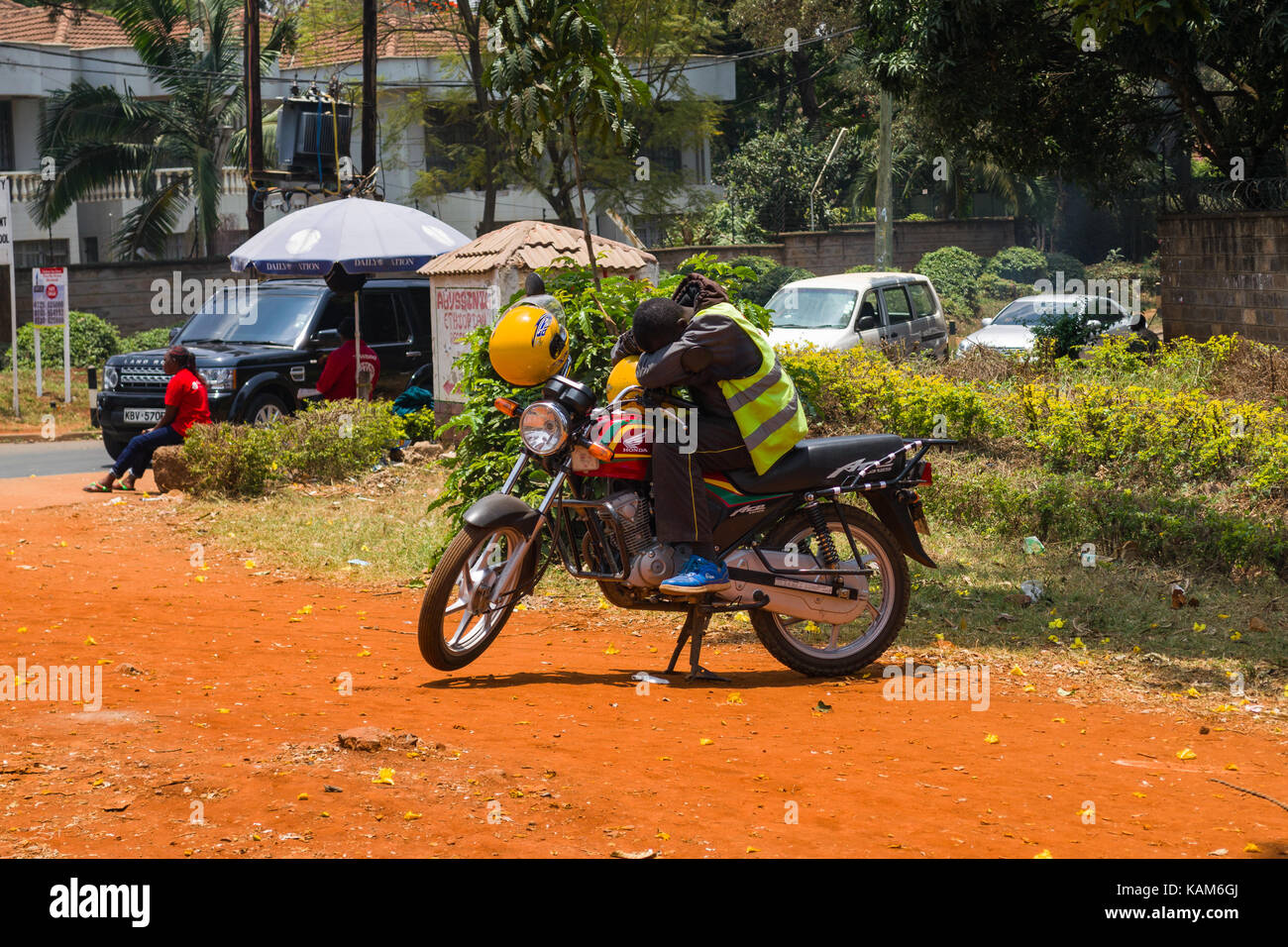 Chauffeur de taxi moto boda boda coin couchage sur moto par le bas-côté de la route, Nairobi, Kenya Banque D'Images