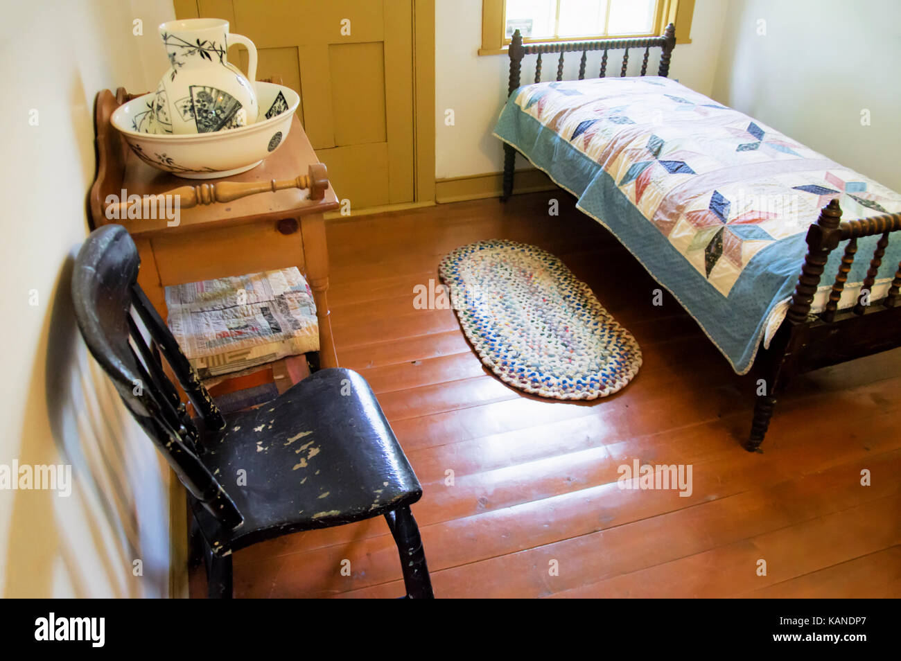 Un lit double avec une table de chevet, une chaise et un pichet. Banque D'Images
