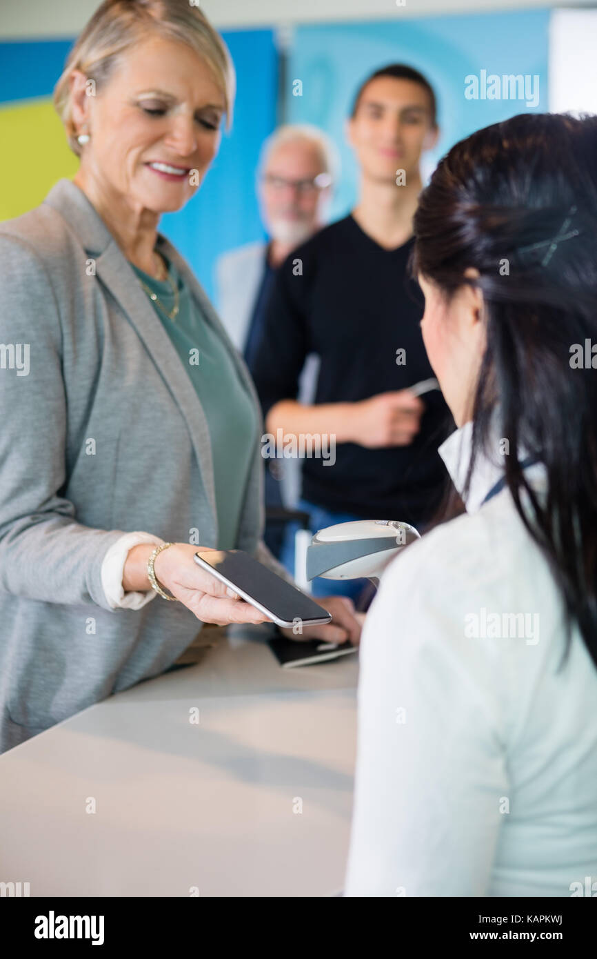 Réceptionniste de l'aéroport code-barres sur l'analyse smart phone détenus par le pas Banque D'Images