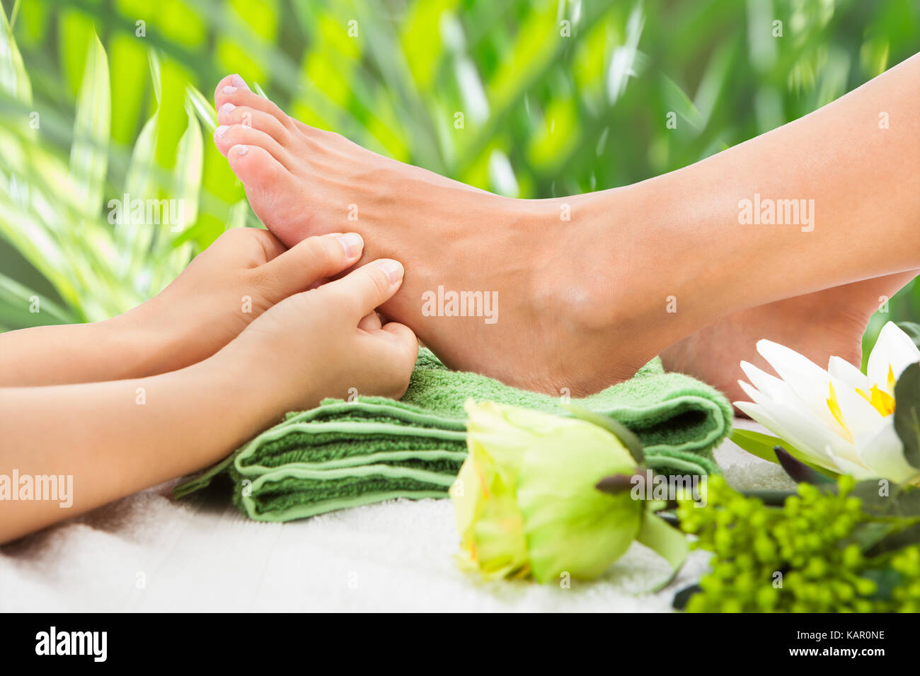 Image recadrée de masseuse massaging woman's foot contre les feuilles beauty spa Banque D'Images